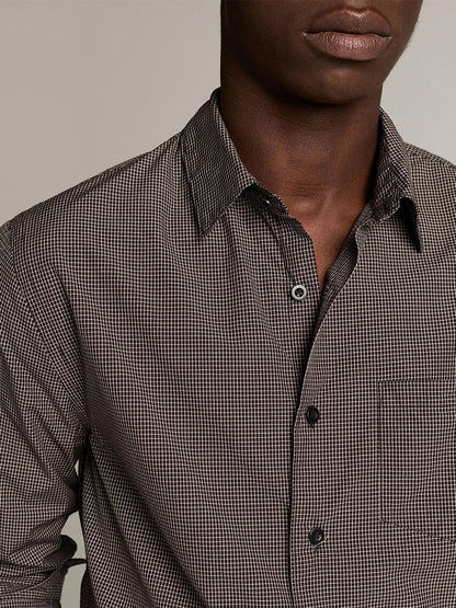A person wearing the Vince McDermott Plaid Cotton Button-Front Shirt in Arabica/Headline Grey, featuring a chest pocket and a brown and black windowpane check pattern, shown from the chest up against a plain background.