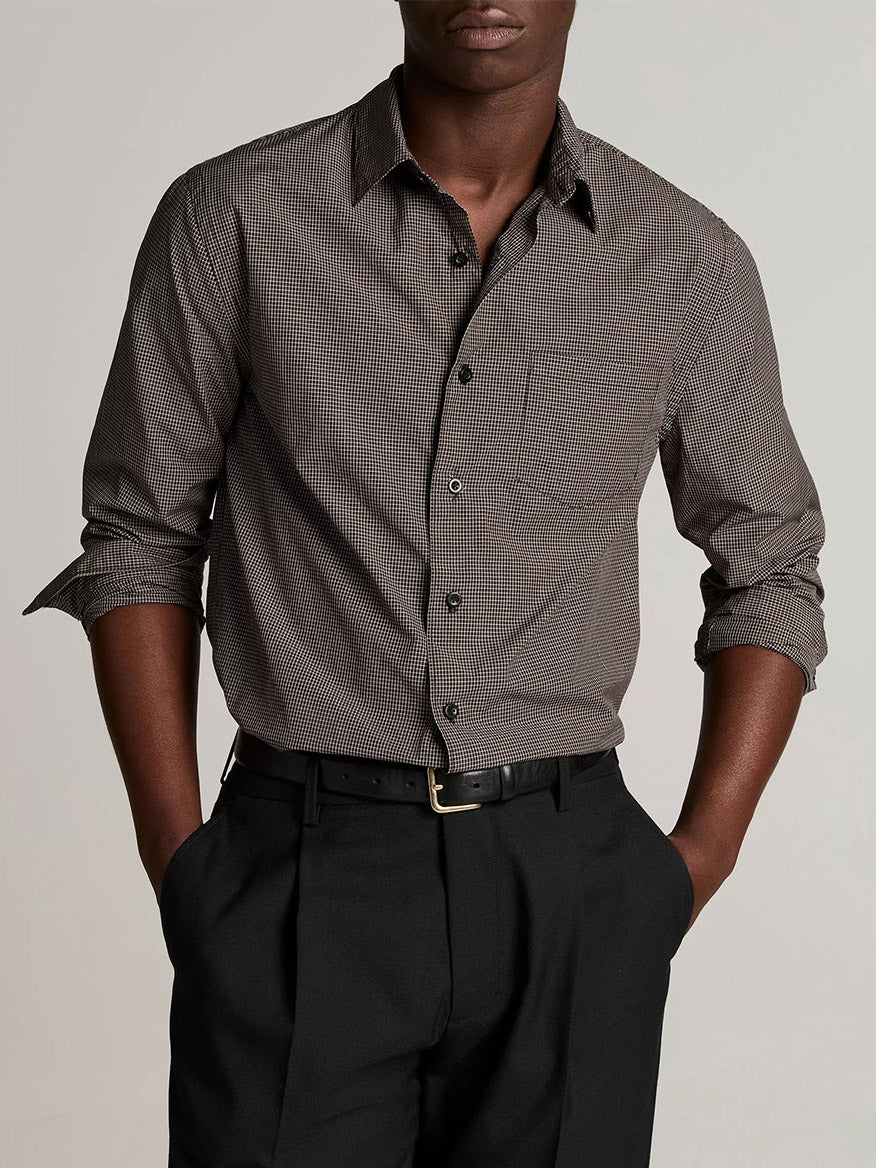 A man wearing the Vince McDermott Plaid Cotton Button-Front Shirt in Arabica/Headline Grey, crafted from cotton poplin, paired with black trousers, stands facing forward with his hands in his pockets against a plain background.