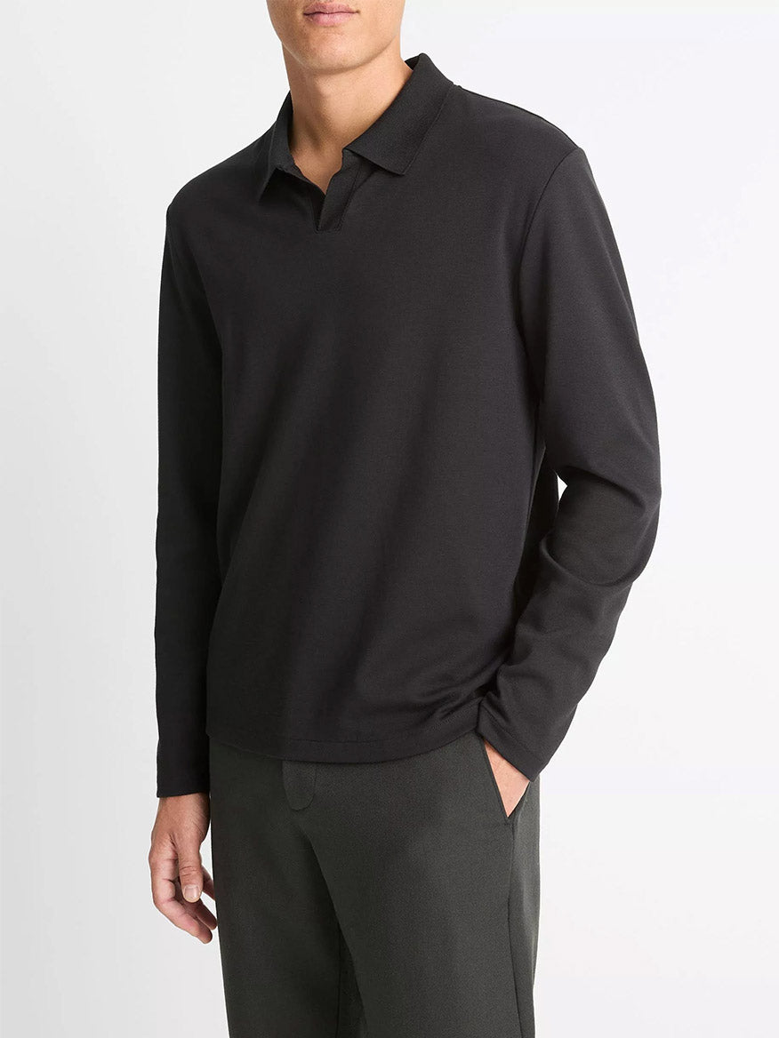 A man wears the Vince Milano Pima Cotton-Blend Johnny-Collar Shirt in black with dark pants, standing against a plain white background.