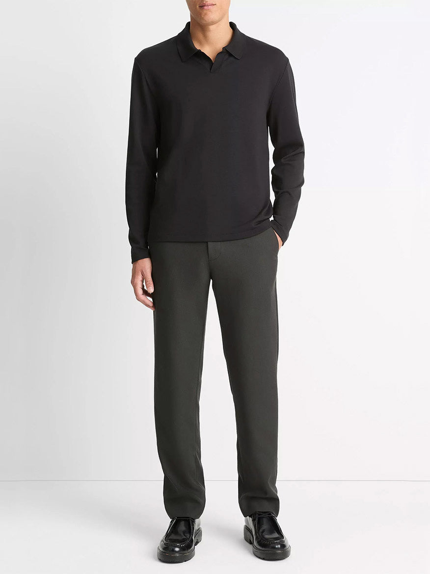 A person stands against a plain background wearing a Vince Milano Pima Cotton-Blend Johnny-Collar Shirt in Black, paired with dark trousers and black shoes, hands in pockets.