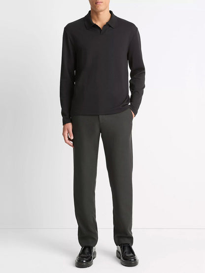 A person stands against a plain background wearing a Vince Milano Pima Cotton-Blend Johnny-Collar Shirt in Black, paired with dark trousers and black shoes, hands in pockets.