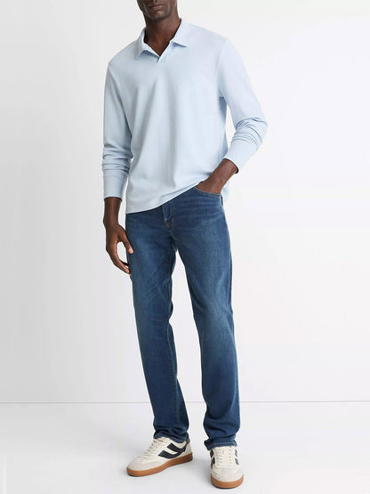 A person wearing the Vince Milano Pima Cotton-Blend Johnny-Collar Shirt in Whitecap, blue jeans, and white sneakers stands against a plain white background.