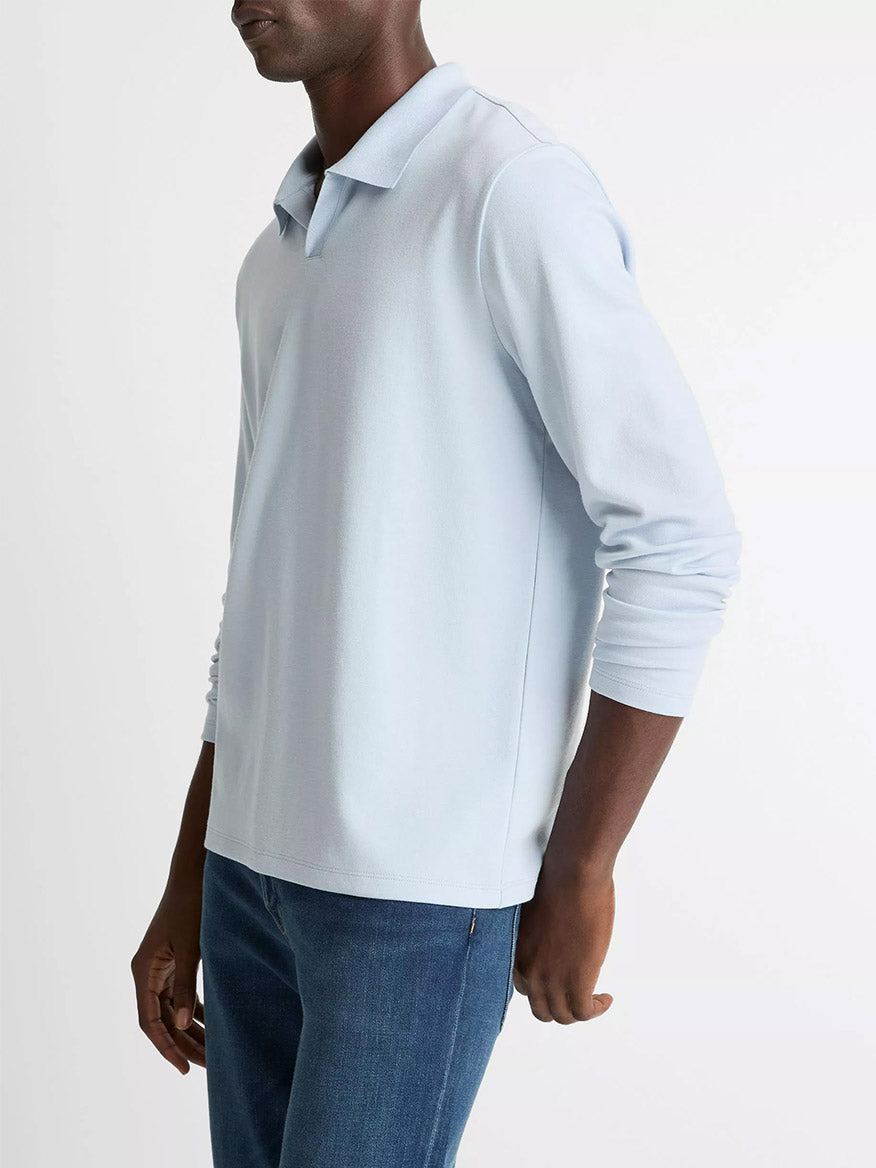 A man wearing the Vince Milano Pima Cotton-Blend Johnny-Collar Shirt in Whitecap and blue jeans stands against a plain white background.