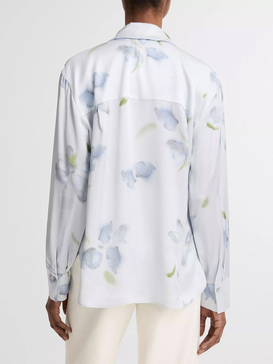 Person wearing the Vince Petal Blur Silk Relaxed Button-Front Shirt in Soft Grey, featuring long sleeves, Agoya shell buttons, and a light blue and green floral pattern; shirt shown from the back.