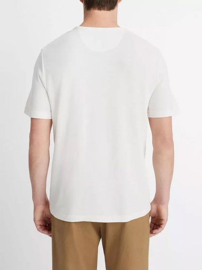 A person from behind wearing a Vince Pima Cotton Piqué Crew Neck T-Shirt in Alabaster and beige trousers.