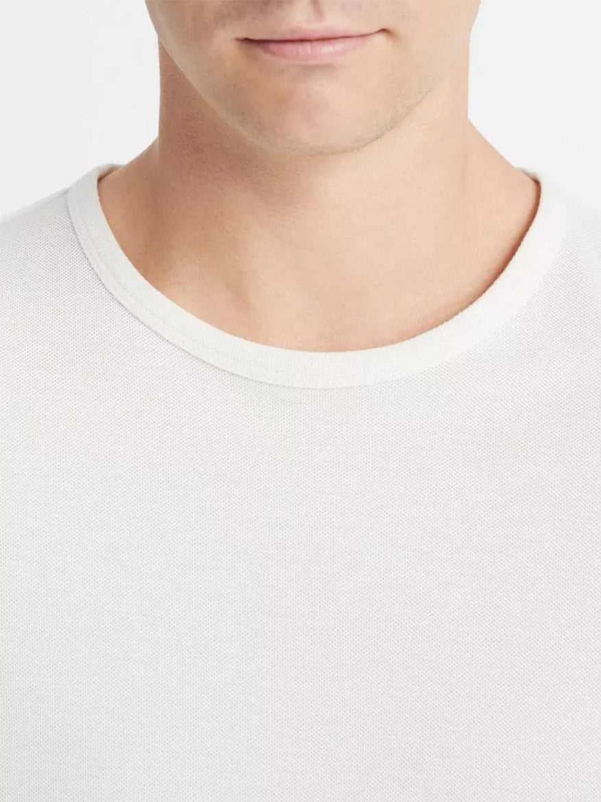 A close-up of a person wearing a white Vince Pima Cotton Piqué Crew Neck T-Shirt in Alabaster.
