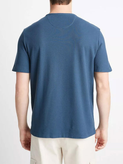 Rear view of a man wearing a Vince Pima Cotton Piqué Crew Neck T-Shirt in Deep Indigo and cream pants.