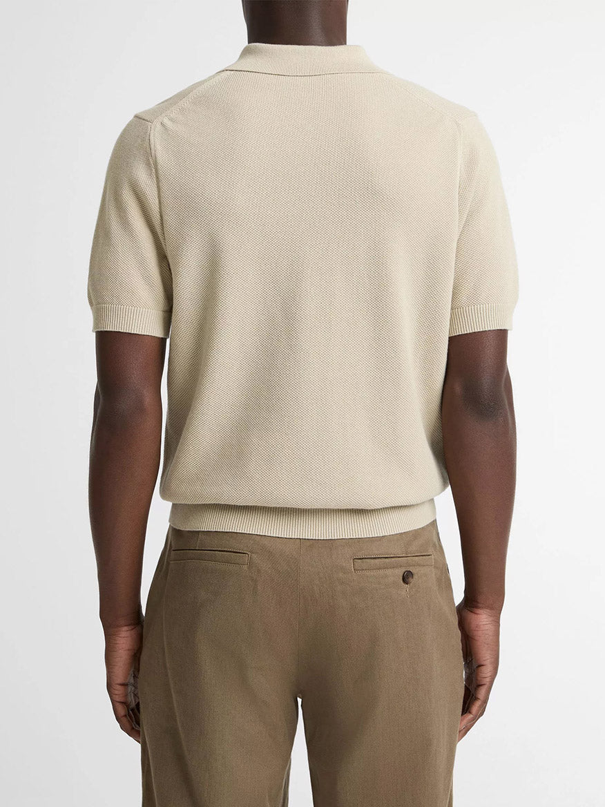 A person seen from the back wears the Vince Cotton-Cashmere Piqué Zip Polo Sweater in Parchment with light brown trousers, standing against a plain background.