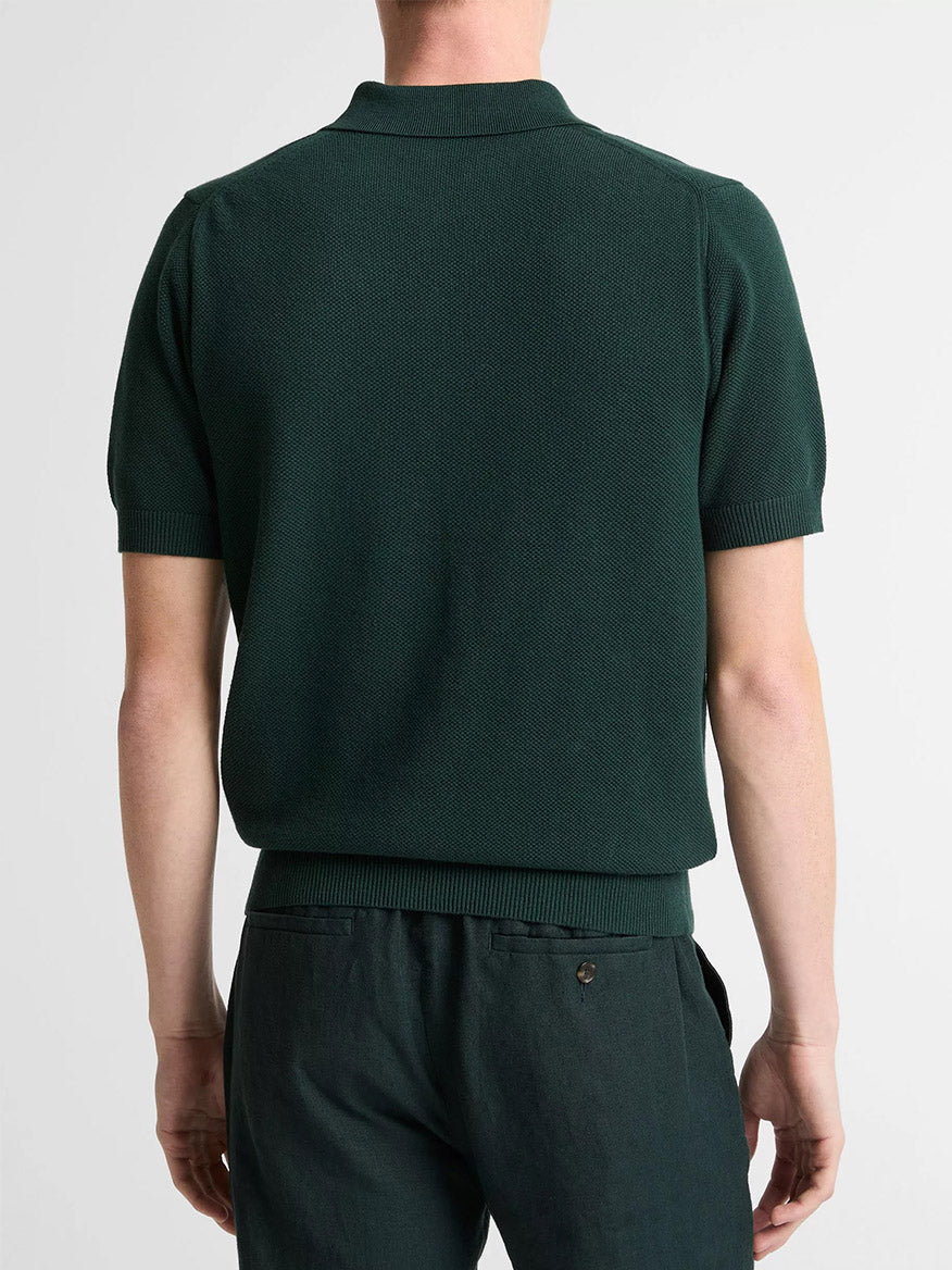 A person wearing the Vince Cotton-Cashmere Piqué Zip Polo Sweater in Seaweed stands with their back to the camera against a plain background, paired with matching pants.