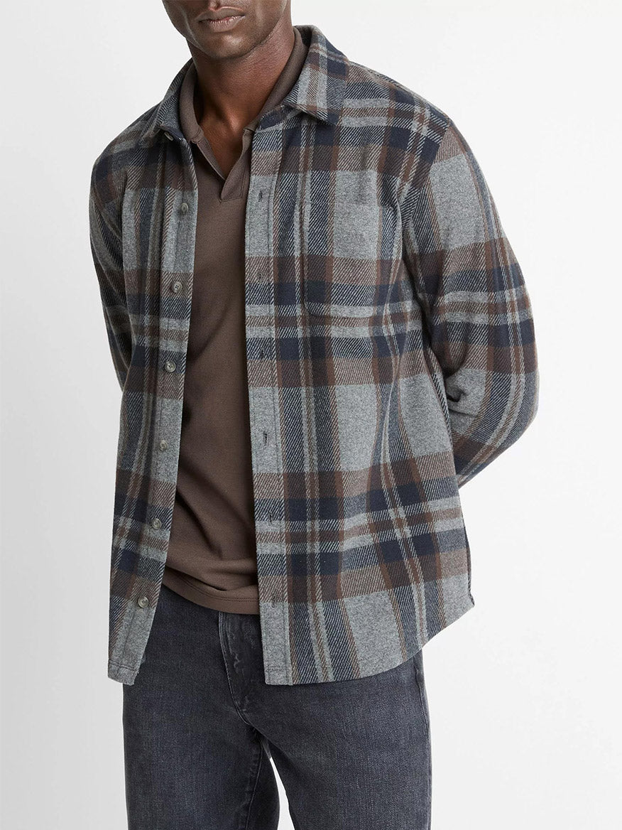A man wears the Vince Plaid Cotton-Blend Shirt Jacket in Medium Heather Grey Combo over a dark polo and black jeans, standing against a plain background.