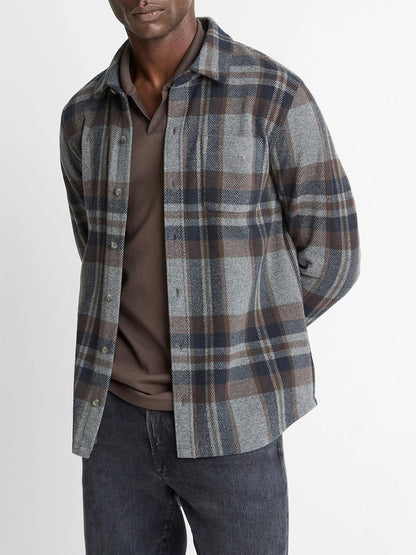 A man wears the Vince Plaid Cotton-Blend Shirt Jacket in Medium Heather Grey Combo over a dark polo and black jeans, standing against a plain background.