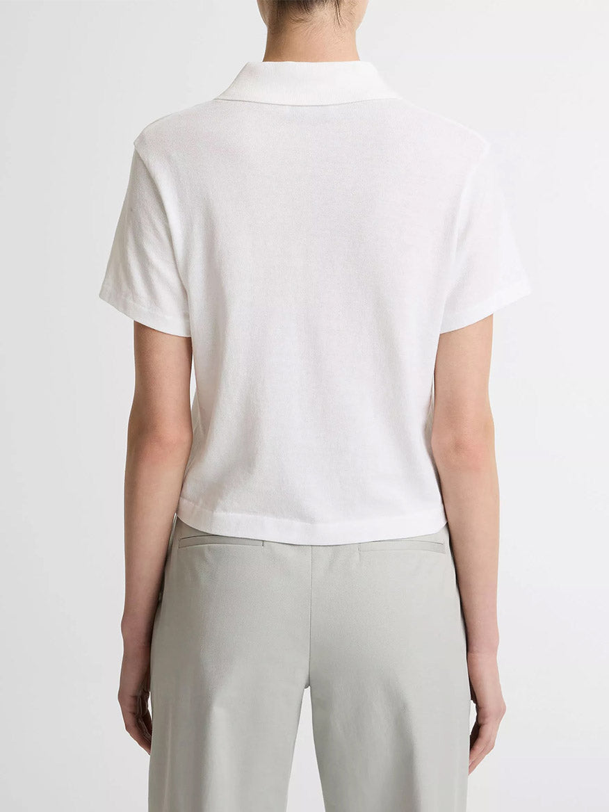A person faces away from the camera, wearing the Vince Cotton Cropped Pocket Polo in Optic White and light gray pants, set against a plain background.