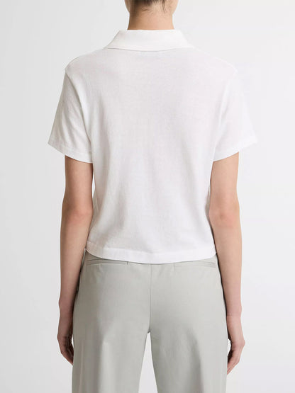 A person faces away from the camera, wearing the Vince Cotton Cropped Pocket Polo in Optic White and light gray pants, set against a plain background.