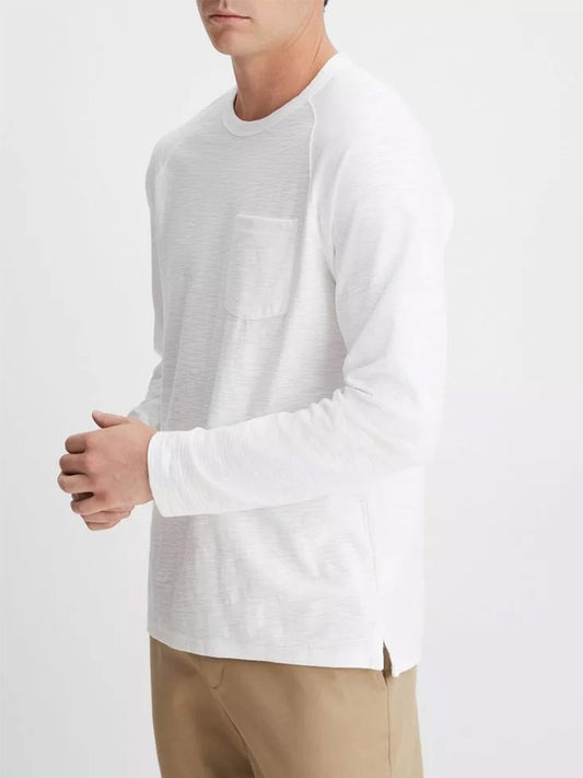 A person is wearing an Optic White Vince Cotton Long Sleeve Pocket Crew T-Shirt with khaki pants, standing against a plain background.