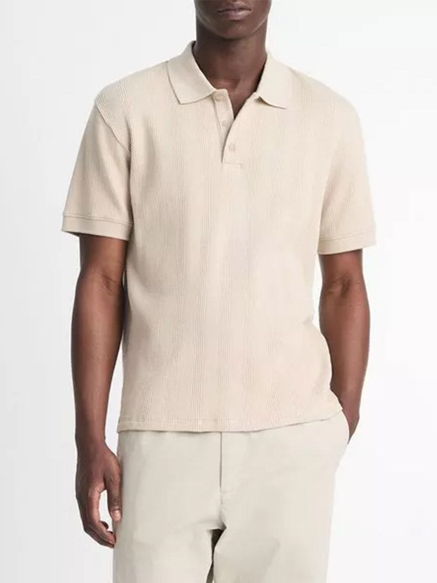 A person wearing a Vince Variegated Pima Cotton Polo Shirt in Dark Morning Haze and matching beige pants stands against a white background.