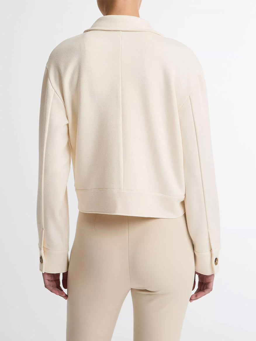 A person is shown from the back against a white background wearing the Vince Ponte Knit Jacket in Off-White, styled as a perfect transitional layer with beige fitted pants.