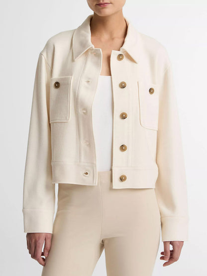 A woman wears the Vince Ponte Knit Jacket in Off-White, featuring chest pockets and a cropped silhouette, layered over a white top and beige pants, standing against a plain background.