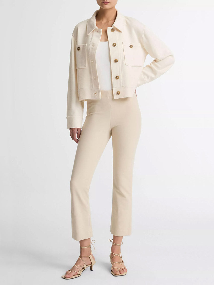 A person wearing the Vince Ponte Knit Jacket in Off-White over a white top, with beige fitted pants and beige strappy heeled sandals, stands against a plain white background.