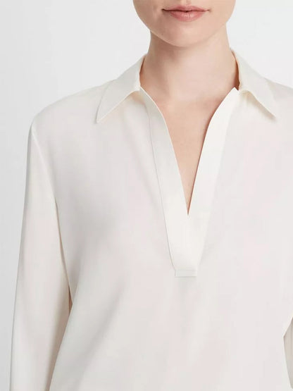 A close-up of a person wearing an elegant Vince Stretch-Silk Long-Sleeve Polo Blouse in Off-White.
