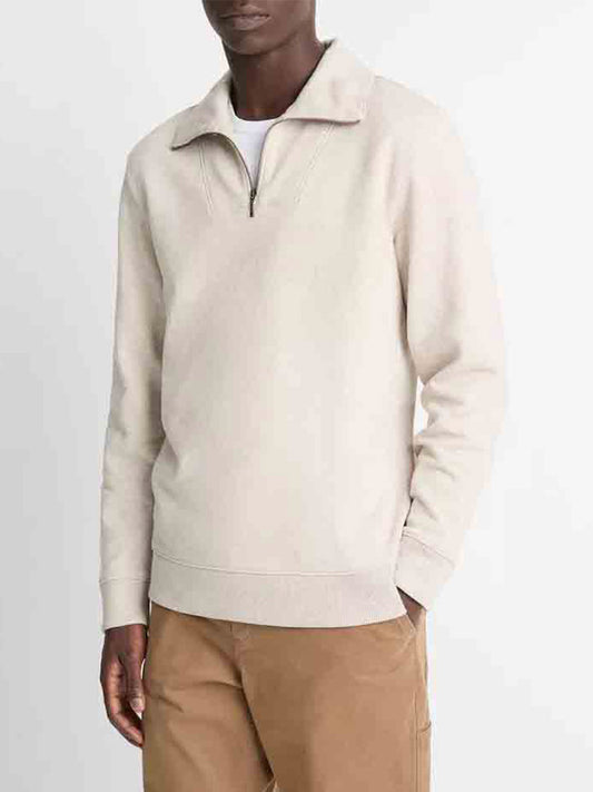 A person wearing a Vince Cotton-Blend Mock Neck Quarter-Zip Pullover in Heather Sheep and brown cotton-blend twill pants stands with one hand in their pocket against a plain background.