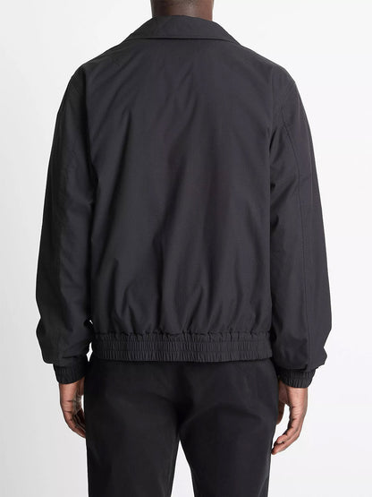 Someone is shown from the back against a plain white background wearing the Vince Italian Cotton Ripstop Bomber Jacket in Black and black pants.