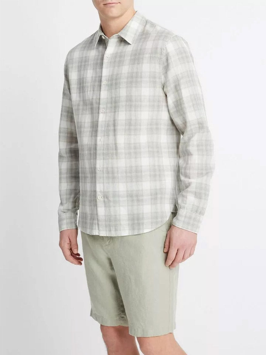 Man wearing a Vince Salton Plaid Long-Sleeve Shirt in Alabaster/Dried Cactus with linen-cotton construction and green shorts standing against a neutral background, offering lightweight comfort.