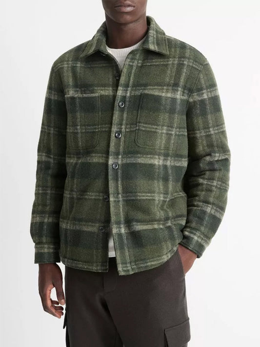 The person is dressed in a Vince Sherpa-Lined Plaid Shirt Jacket in Night Moss Combo with a button-front closure over a light shirt, complemented by dark pants.