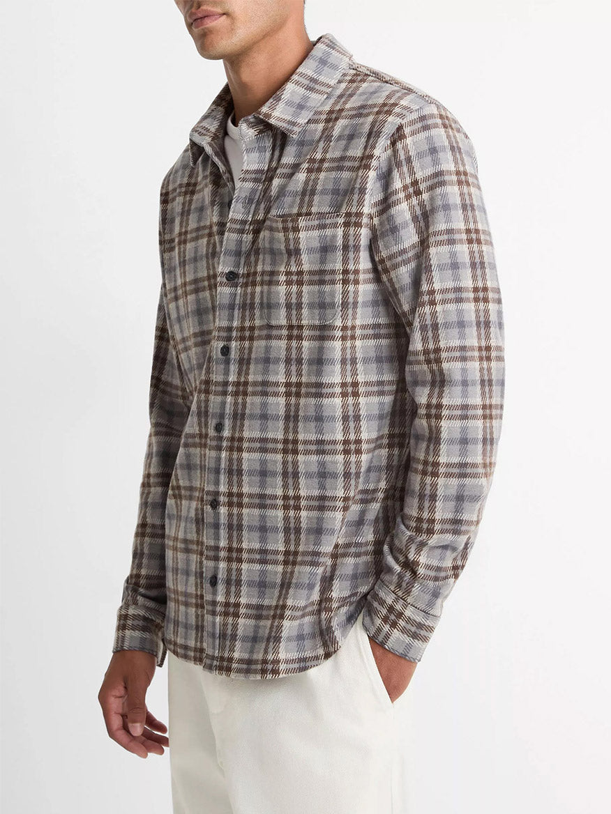 A man wears the Vince Plaid Cotton-Blend Shirt Jacket in Heather Fog Combo with long sleeves and white pants, standing against a plain white background.