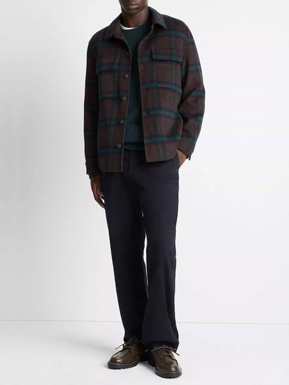 A person wears the Vince Plaid Splittable Wool-Blend Shirt Jacket in Coastal Country Racer, paired with a green textured sweater, black trousers, and brown shoes, standing against a plain white background.