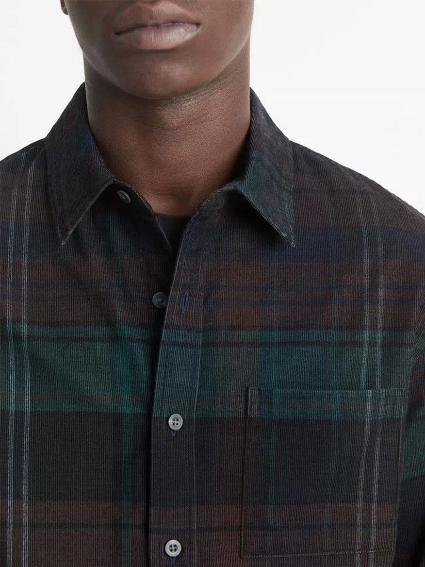 An individual wearing the Vince Sierra Plaid Cotton Corduroy Shirt in Surplus Olive/Ivy Sky, which features a plaid pattern, buttons, and a chest pocket, facing forward.