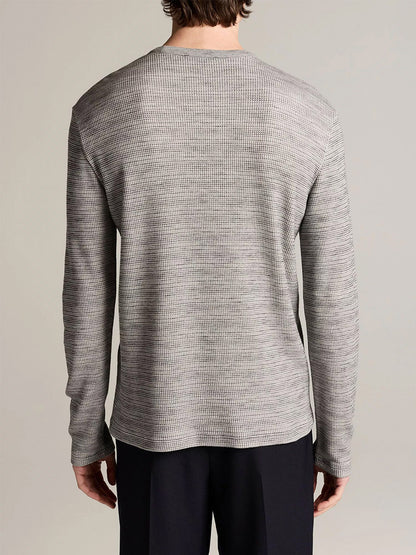 Person facing away from camera wearing the Vince Space-Dye Cotton-Blend Thermal Long-Sleeve T-Shirt in Late Evening Combo and black pants, standing against a plain background.