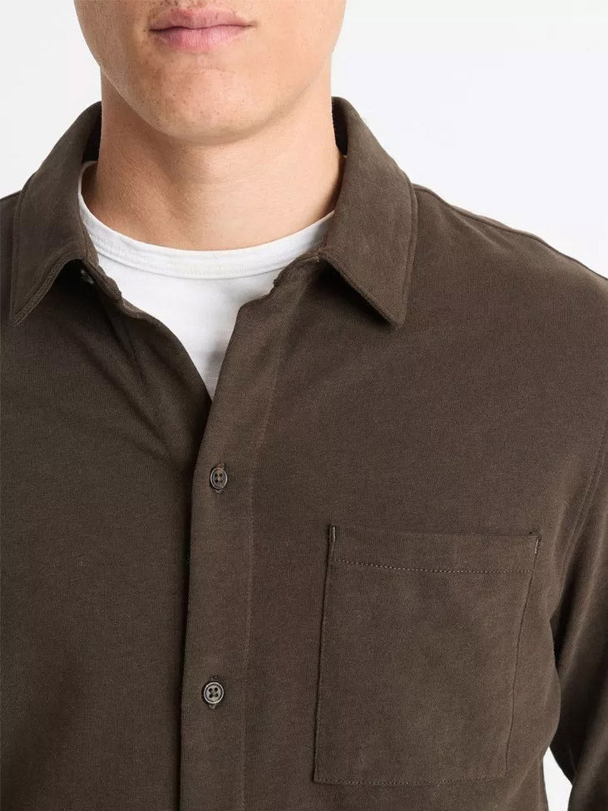 An individual dons a Vince Sueded Cotton Jersey Button-Front Shirt in Night Moss, layered over a soft, white cotton jersey t-shirt, visible from the chest up.