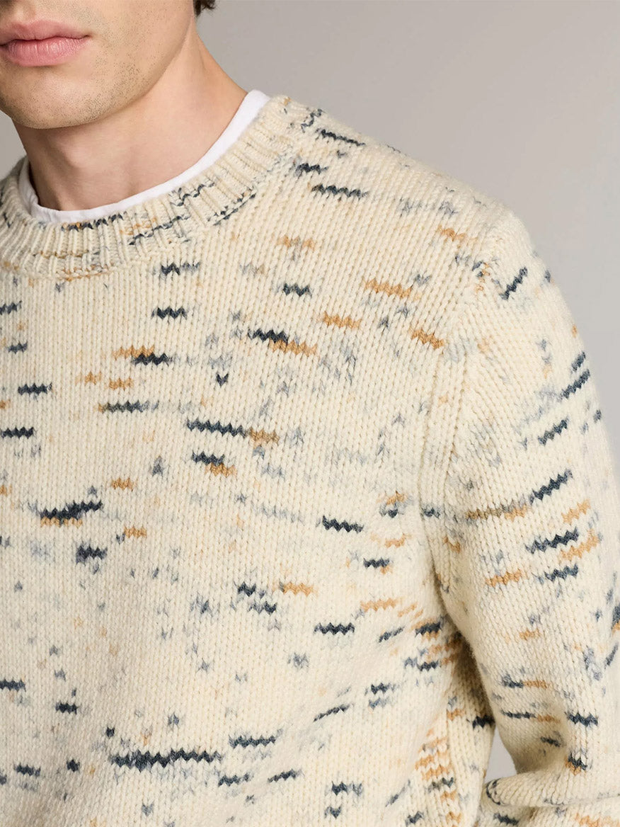 A man wearing the Vince Super Space-Dye Merino Wool Sweater in Bone Combo with a black and brown speckled design, shown from the shoulders up.