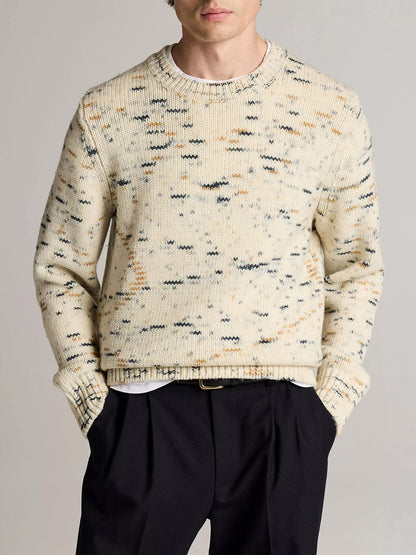 A person wears the Vince Super Space-Dye Merino Wool Sweater in Bone Combo over a white shirt with black trousers, standing against a plain background.