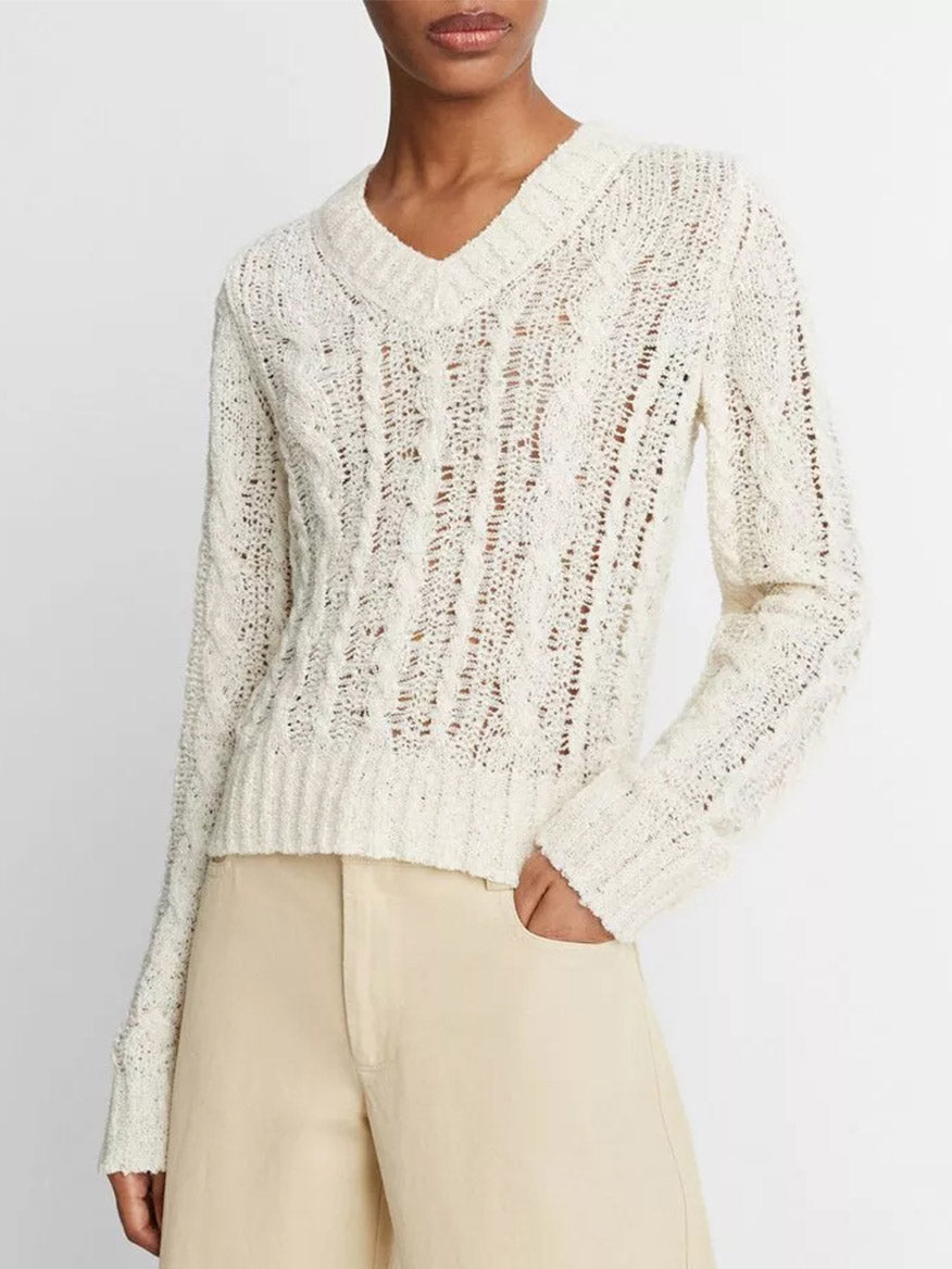 Woman wearing a white Vince Textured Cable V-Neck Sweater in Cream and beige pants.