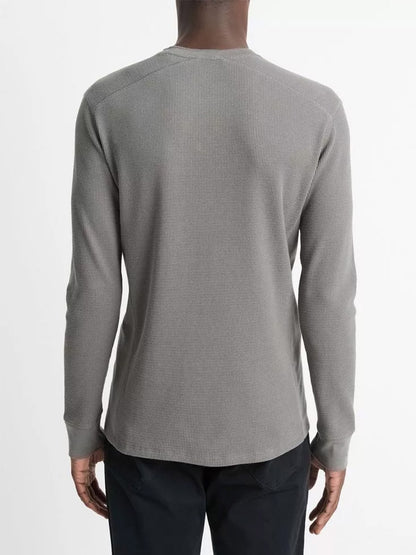 Rear view of a person wearing the Vince Thermal Pima Cotton-Blend Long-Sleeve T-Shirt in Iron paired with dark pants against a plain background.