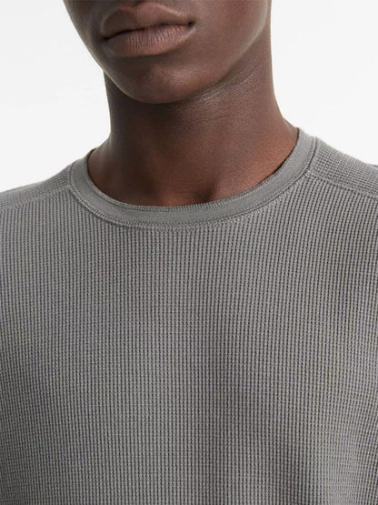 The image features a person shown from the shoulders up, wearing the Vince Thermal Pima Cotton-Blend Long-Sleeve T-Shirt in Iron, set against a plain background.