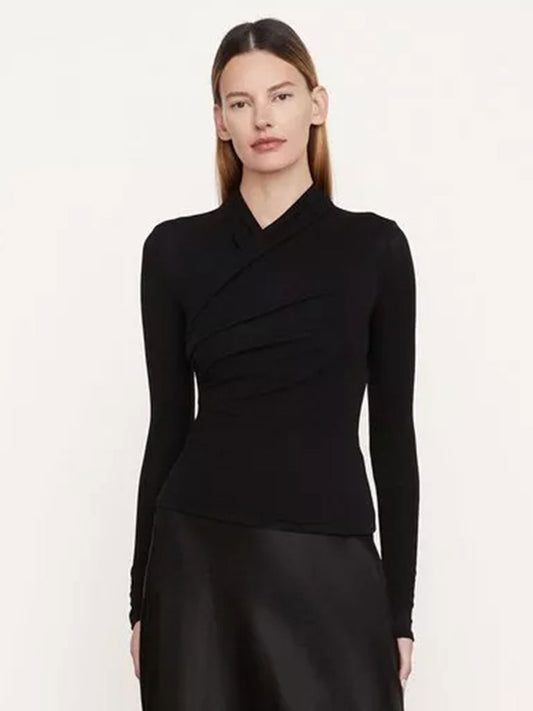 A person with long hair is wearing a Vince Fixed Wrap Long-Sleeve Top in Black, made of soft jersey and featuring a fitted, draped, overlapping design on the front. They are standing against a plain, light-colored background.