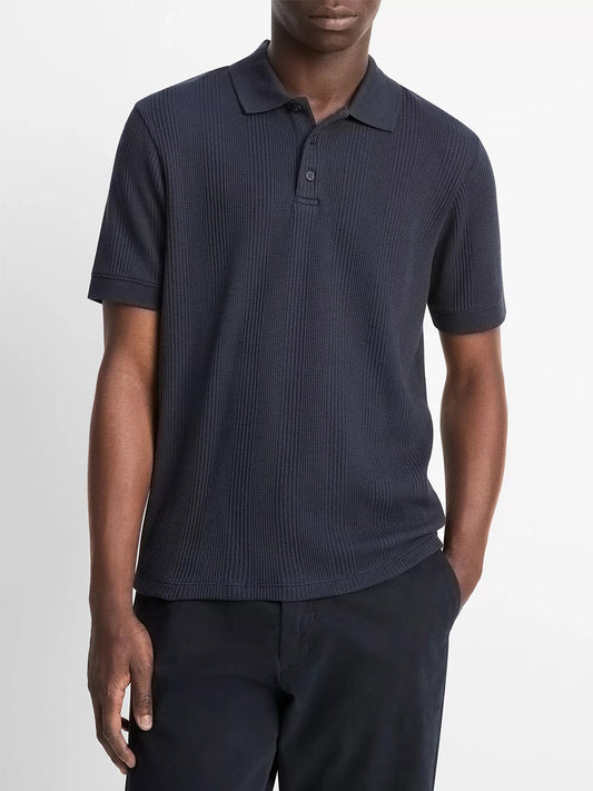 A man wearing the Vince Variegated Pima Cotton Polo Shirt in Coastal Blue and matching pants stands with his hands in his pockets against a plain white background.