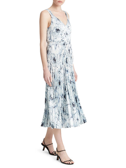 Woman wearing a summery sleeveless, v-neck, printed midi slipdress with pleated skirt named Vince Washed Lily Pleated Slipdress in Pale Azure, paired with black strappy heels.