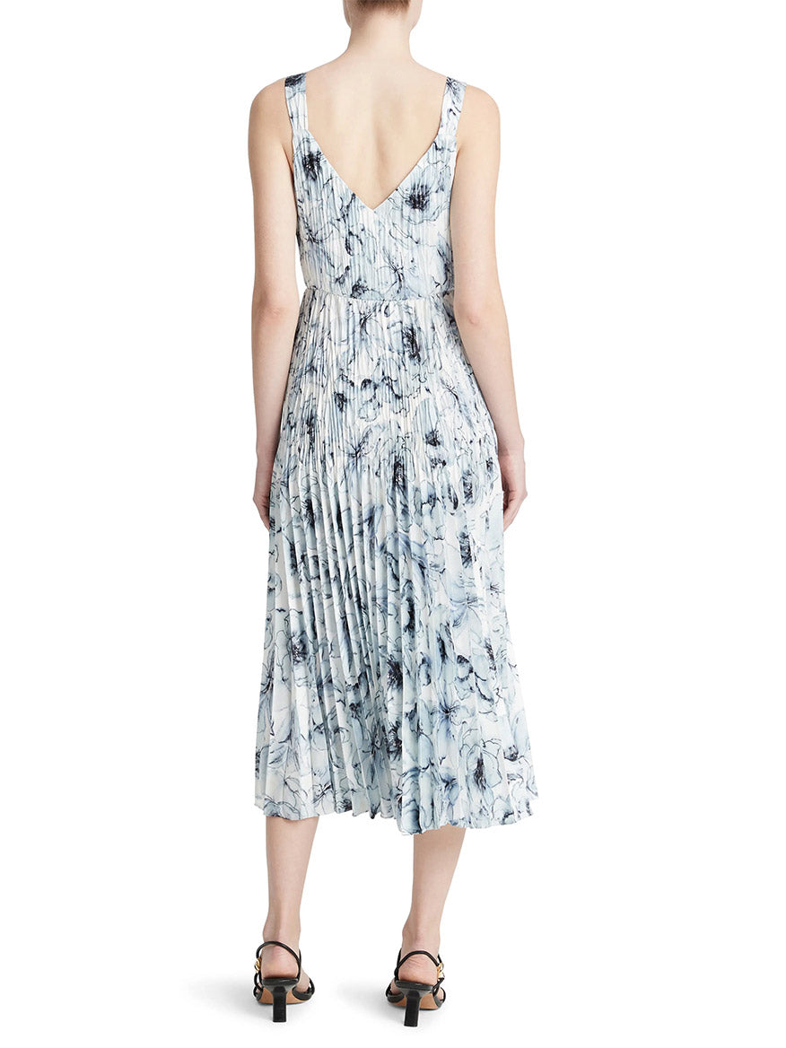Woman viewed from behind wearing a Vince Washed Lily Pleated Slipdress in Pale Azure with a v-back neckline, paired with black heeled sandals.