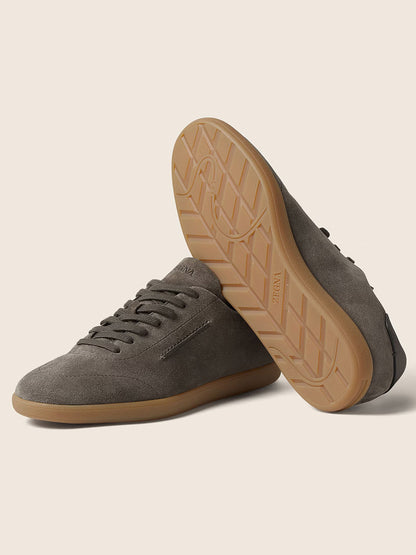 The Zegna 232 Suede Sneakers in Dark Taupe feature gum rubber soles, with one shoe upright and the other on its side displaying the tread. This stylish pair is expertly made in Italy.