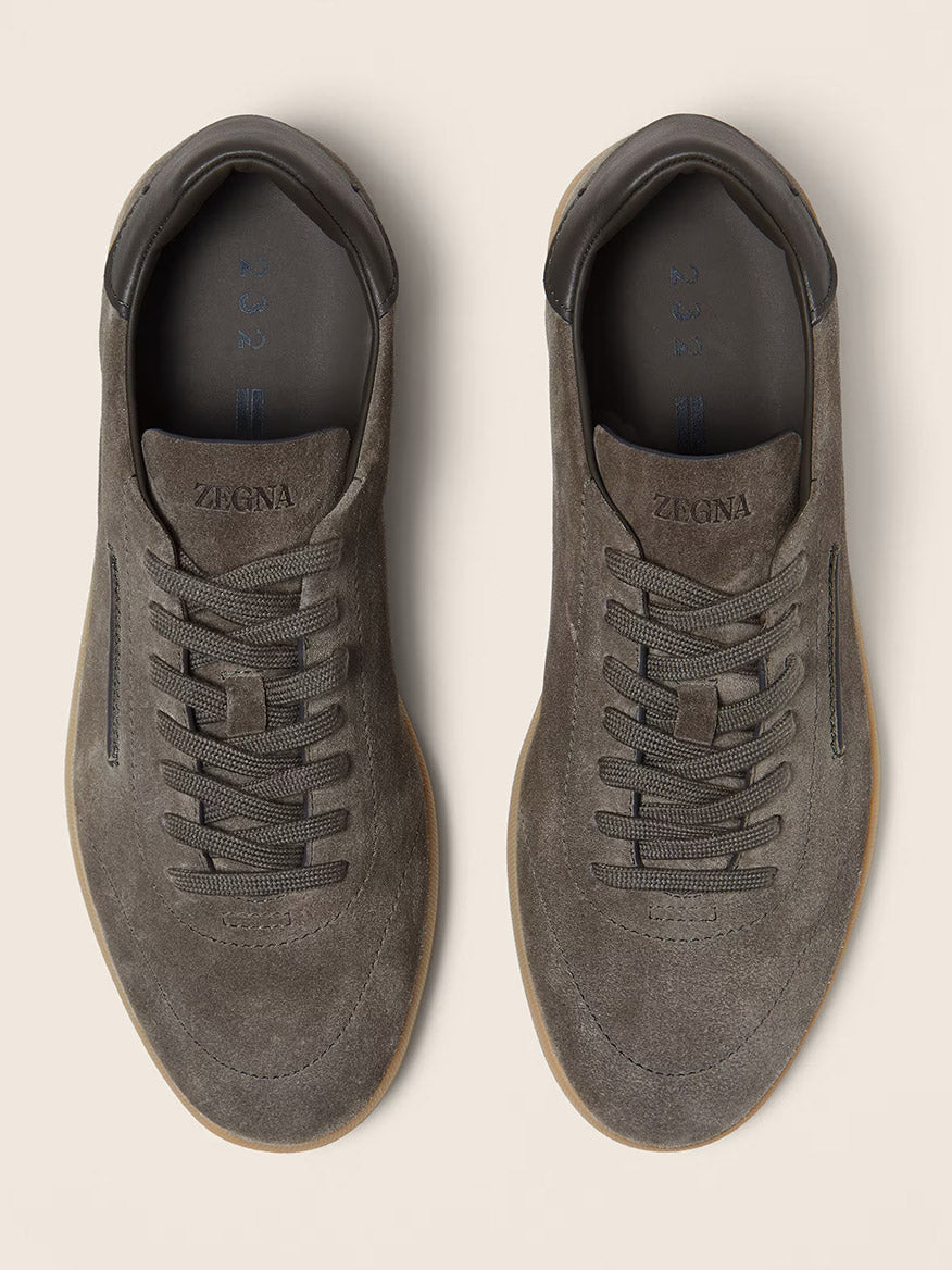 A pair of Zegna 232 Suede Sneakers in Dark Taupe, made in Italy with "ZEGNA" branding on the tongue, shown from above on a light beige background.