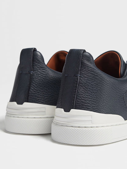 Close-up of the back view of Zegna Navy Blue Deerskin Triple Stitch™ Sneakers featuring white rubber soles on a plain background.