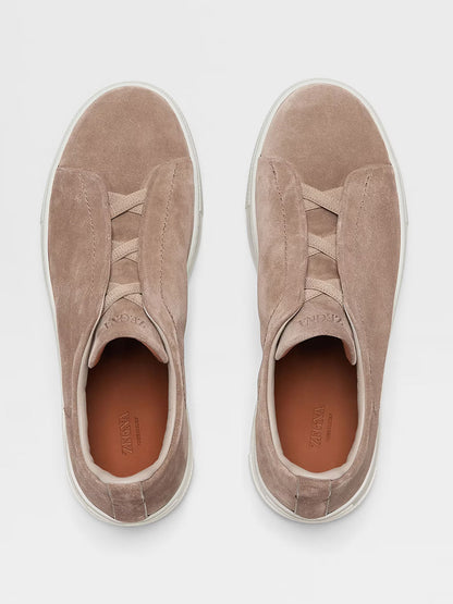 Aerial view of the Zegna Beige Suede Triple Stitch Low Top Sneaker, showcasing their beige suede slip-on design with white rubber soles and elastic bands across the top.