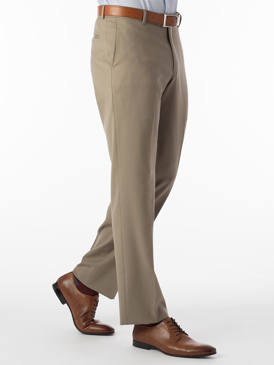 A man in a Ballin Theo Comfort 'EZE' Modern Flat Front Pant in British Tan made of wool gabardine is walking on a white background.