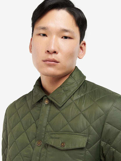 A man wearing a Barbour Newbie Quilted Jacket in Olive with stud fastenings.