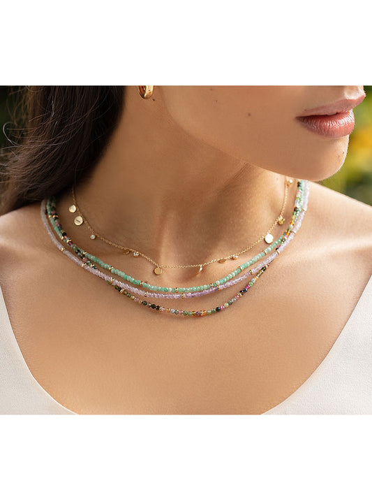 A woman wearing an EF Collection Birthstone Necklace with Gold Rondelles - Rainbow Tourmaline adorned with multi-colored beads.