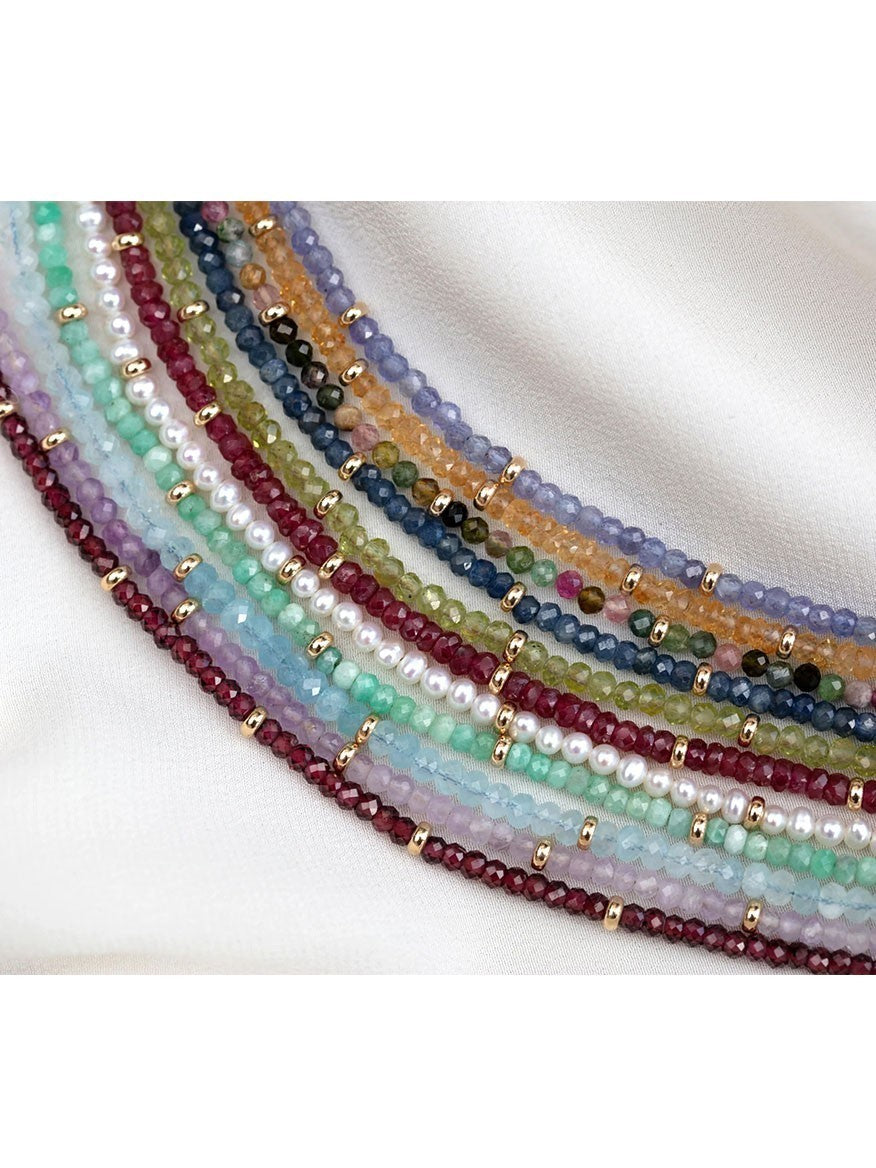 A rainbow tourmaline birthstone necklace featuring tourmaline beads, set against a crisp white background.