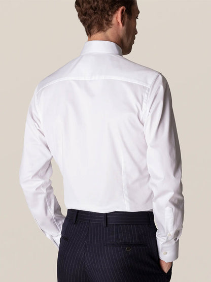 Man standing with his back to the camera, wearing an Eton Slim Fit White Stretch Twill Dress Shirt and pinstriped trousers.
